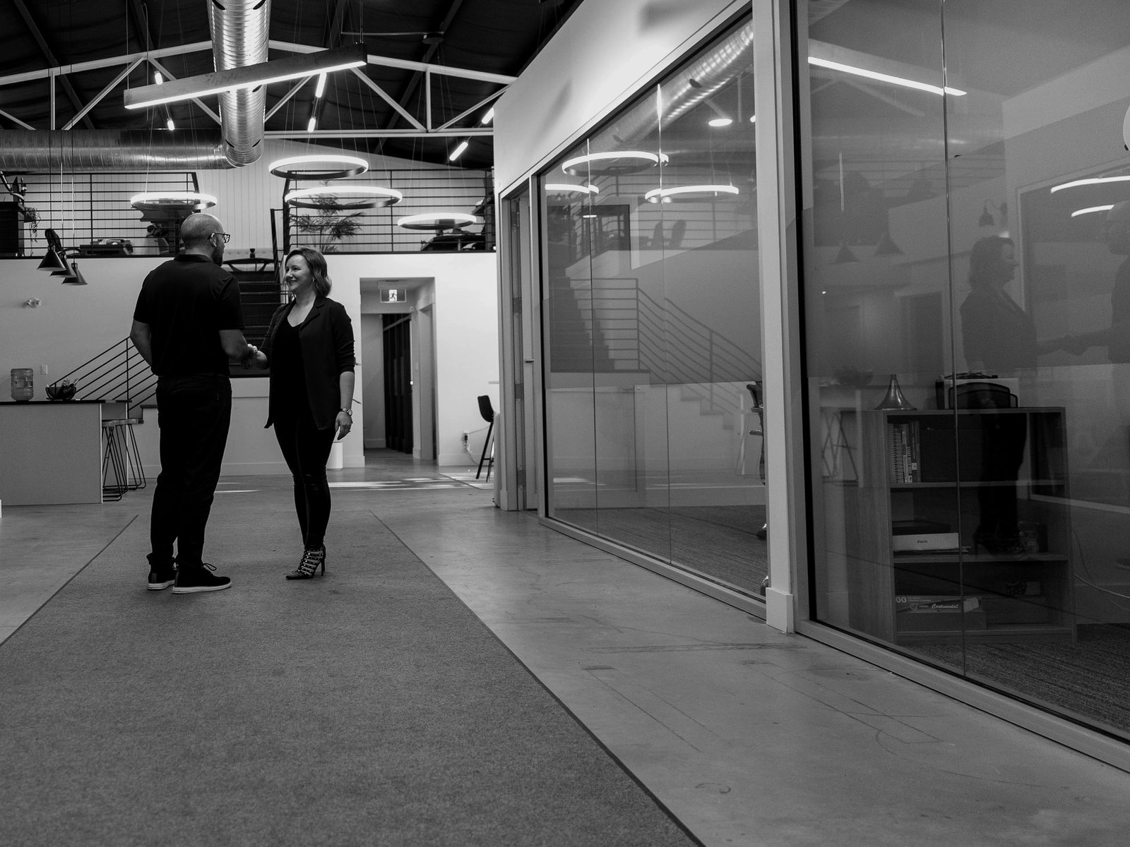 The property management office on a working day: two people talking in the atrium, glass-walled offices beside them.