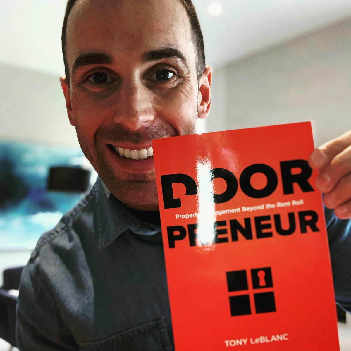 Tony LeBlanc holding up a copy of Doorpreneur, smiling.