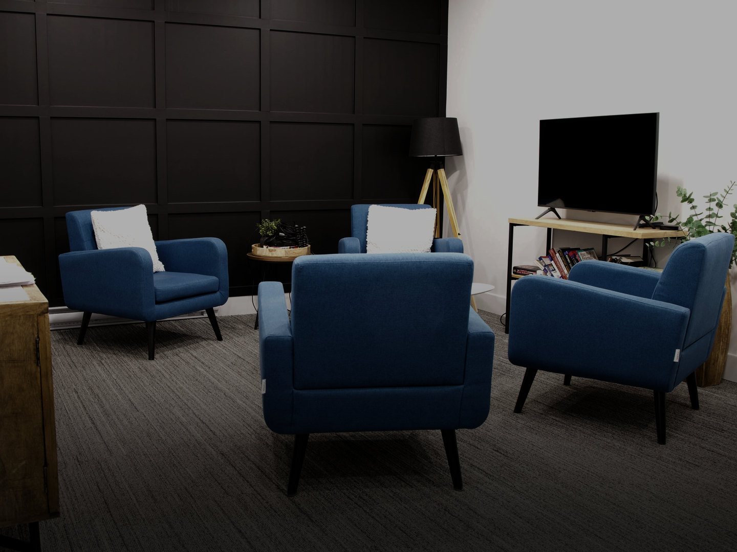 The lounge at the property management company’s office, with blue armchairs against a dark panelled wall.