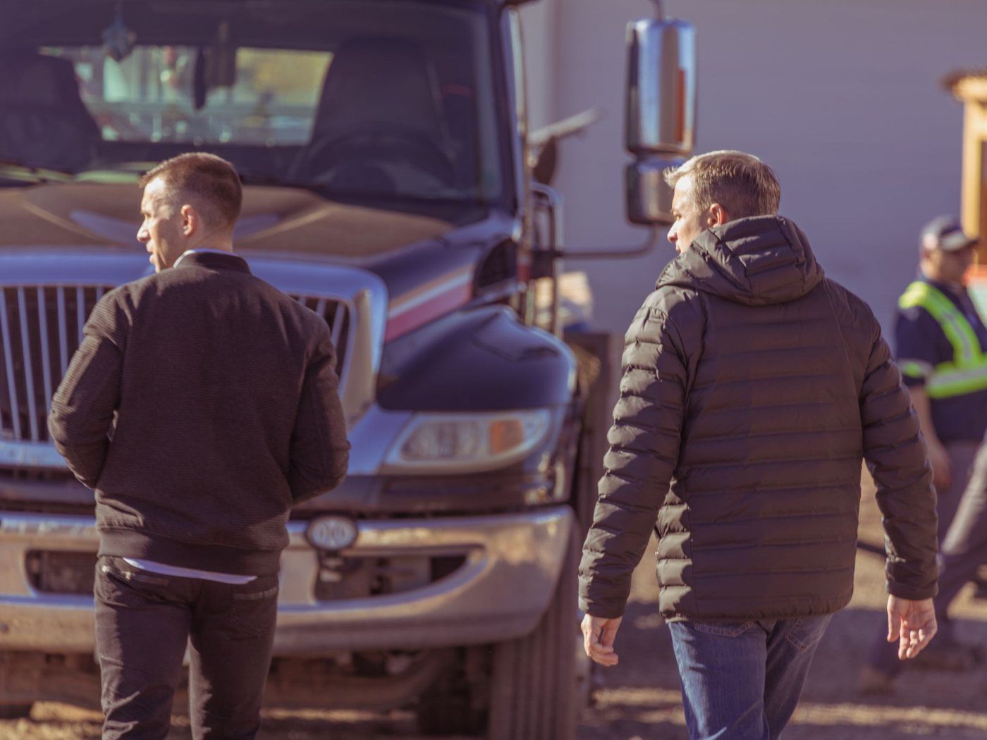 Tony and a partner walking a work site toward a truck, crew in the yard